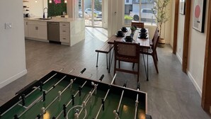 A spacious kitchen with a dining area, a foosball table, and a large window providing a view of the outside. - Naples Island rooftop deck/bbq AC & 2 car garage (Long Beach)