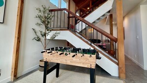 A spacious interior with a high ceiling, a wooden staircase, and a foosball table. - Naples Island rooftop deck/bbq AC & 2 car garage (Long Beach)
