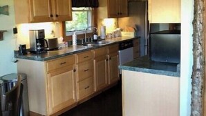 Una cocina con armarios de madera, una isla central, horno empotrado e iluminación colgante.