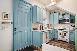 A kitchen with blue cabinets, a microwave, a stove, and a refrigerator.