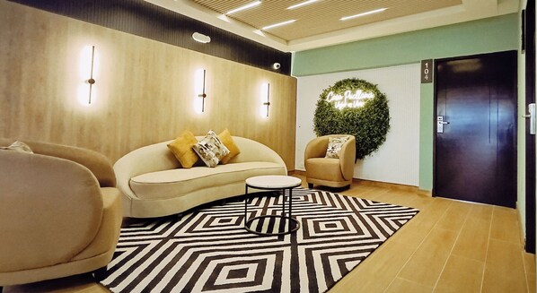 Un área de espera moderna con un sofá, un sillón y una mesita.