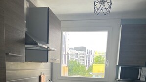 Een moderne keuken met raam, roestvrijstalen apparatuur en een prullenbak.