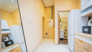 A compact kitchen with white appliances, wooden cabinets, and a visible water heater. - Buda Castle Charming Apartment 70 m² (Budapest)