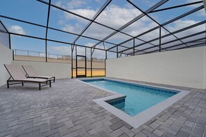 Une piscine intérieure avec un sol carrelé et deux chaises longues.