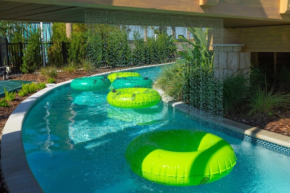 A swimming pool with three green inflatable rings and a stone wall.