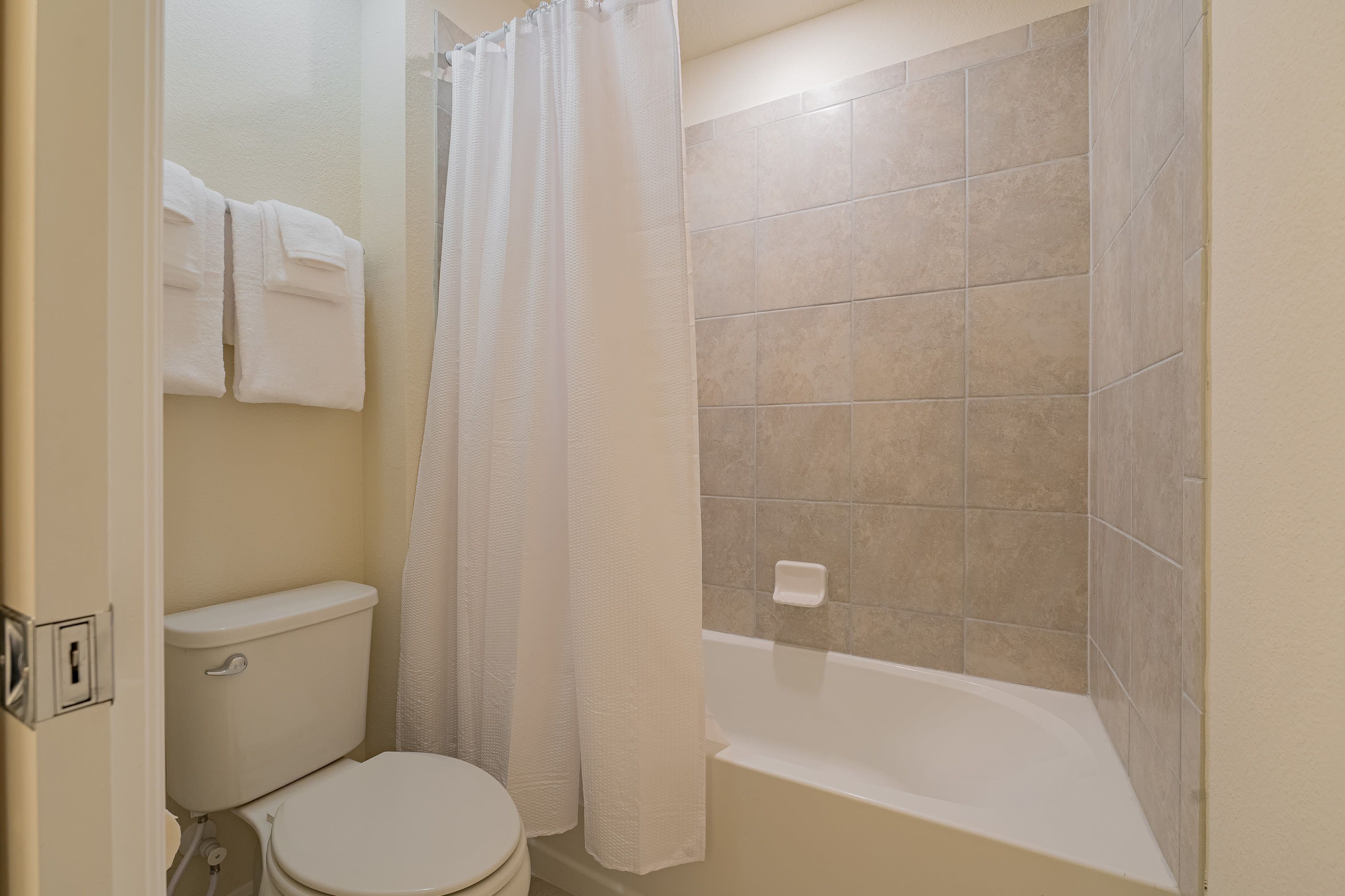 A bathroom with a toilet, a bathtub, and a shower curtain.