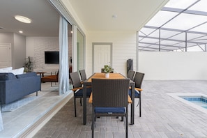 A spacious patio with a dining table, chairs, a sofa, and a small pool.
