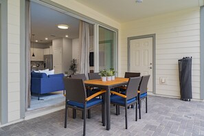 A patio with a table and chairs, a blue sofa, and a sliding glass door leading to a living area.