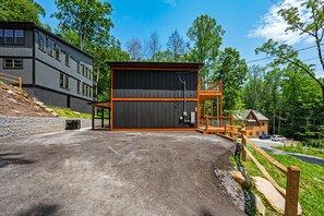 Situated in a lush environment, this building features a large entrance area with a wooden deck and a smaller adjacent structure with an orange roof.