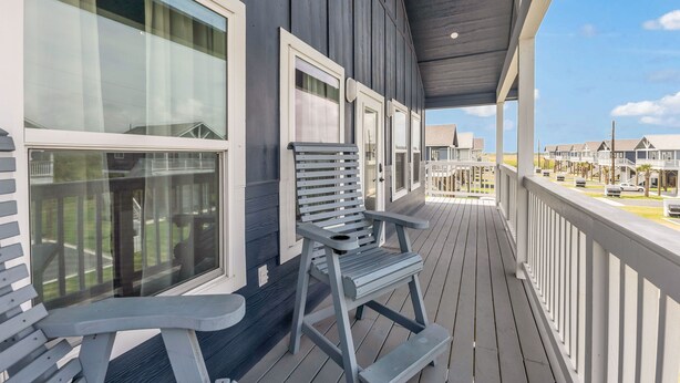 A covered porch with a bench and a view of a row of houses.