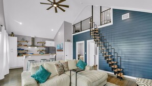 A modern living room with a sectional sofa, a small coffee table, and a staircase leading to an upper level.
