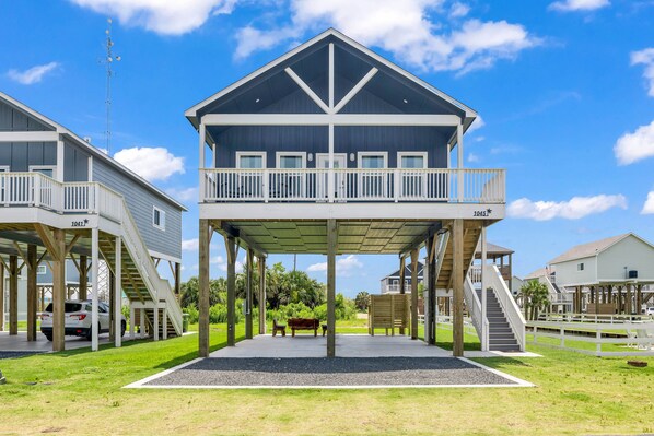 Un edificio a due piani con un balcone, una zona coperta con una panchina e una scala che conduce al piano superiore.