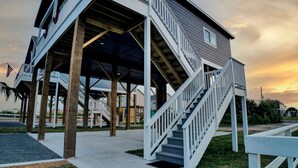 A waterfront house with a covered porch and a staircase leading to the upper level.