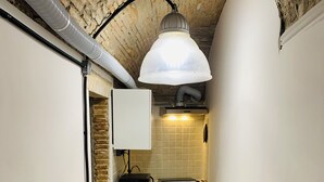 A narrow kitchen with a brick floor, white cabinets, and a hanging light fixture. - Loft in Pieno Centro Storico con Arredamenti di Design e Ingresso Indipendente (Rieti)