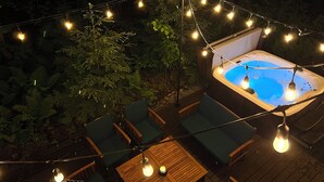 Un jacuzzi rodeado de sillas y mesas de madera, con luces colgantes.