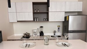 A modern kitchen with a white countertop, stainless steel appliances, and a built-in wine rack. - Studio Toh 210 - Elle Residence (Tulum)
