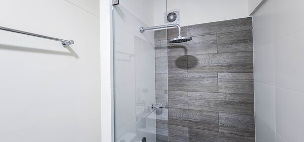 A modern shower with a rain showerhead, a glass door, and a wooden-textured wall.