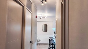 Ein Flur mit modernem Design, der einen hellen Boden, eine Deckenleuchte und einen Spiegel an der Wand zeigt.