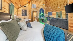 Ein Holzblockhaus-Interieur mit Bett, Sofa und Fernseher.