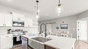 Een moderne keuken met witte kasten, roestvrijstalen apparatuur en een groot eiland.