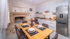 Une cuisine moderne équipée d’une cuisinière intégrée, d’un réfrigérateur et d’un coin repas avec une table dressée pour quatre personnes.