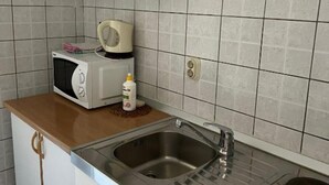 Une cuisine équipée d’un four à micro-ondes, d’une bouilloire et d’un flacon de liquide vaisselle posé sur le plan de travail.