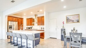 Una cocina moderna con armarios de madera, una isla central con taburetes de bar y un comedor con mesa y sillas.
