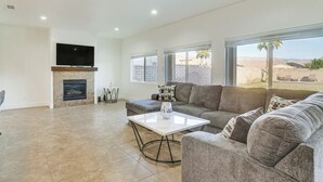 Amplia sala de estar con chimenea, un televisor de pantalla plana grande y un cómodo conjunto de sofá gris.