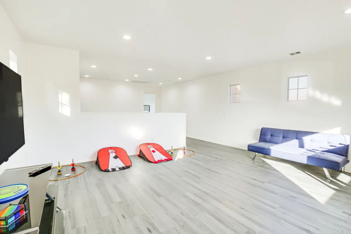 A spacious living room with a blue sofa, a flat-screen TV, and two red exercise bikes.