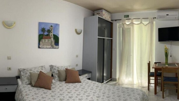 A bedroom with a bed, a desk, a chair, a TV, and a painting on the wall. - Apartments Natali - One Bedroom Apartment with Balcony (APP3) (Podaca)