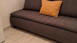 A brown sofa with a single orange cushion in a room with tiled flooring. - Apartments Natali - One Bedroom Apartment with Balcony (APP3) (Podaca)