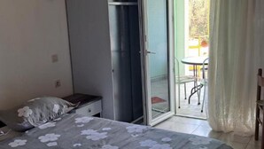 A bedroom with a bed, a nightstand, a sliding glass door leading to an outdoor area with a table and chairs. - Apartments Natali - One Bedroom Apartment with Balcony (APP3) (Podaca)