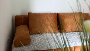 Un sofà marró amb funda acolchida davant d'una paret blanca.