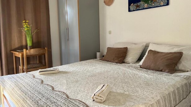 A bedroom with a bed, pillows, a nightstand, a wardrobe, a painting, and a curtain. - Apartments Natali - One Bedroom Apartment with Balcony (APP5) (Podaca)