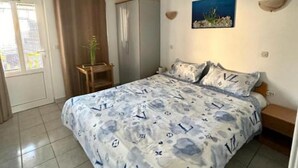 A bedroom with a bed, a nightstand, a wardrobe, and a window with curtains. - Apartments Natali - One Bedroom Apartment with Balcony (APP5) (Podaca)