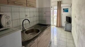 A compact kitchen with a built-in microwave, a sink, and wooden cabinets. - Apartments Natali - One Bedroom Apartment with Balcony (APP5) (Podaca)