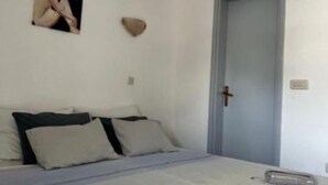 Une chambre à coucher avec un lit, des oreillers, un tableau accroché au mur et une porte.