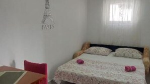 A bedroom with a bed, a chair, a table, and a wall with a drawing of the Eiffel Tower.
