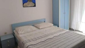 A bedroom with a bed, a nightstand, a wardrobe, and a painting on the wall.