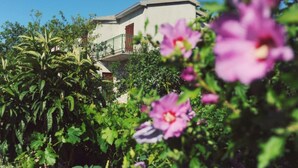 A building with a balcony and a garden with pink flowers. - One Bedroom apartment with Terrace (Šibenik)