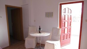 A small, well-lit room with a round table, two chairs, a bottle of wine, and a red door. - One Bedroom apartment with Terrace (Šibenik)