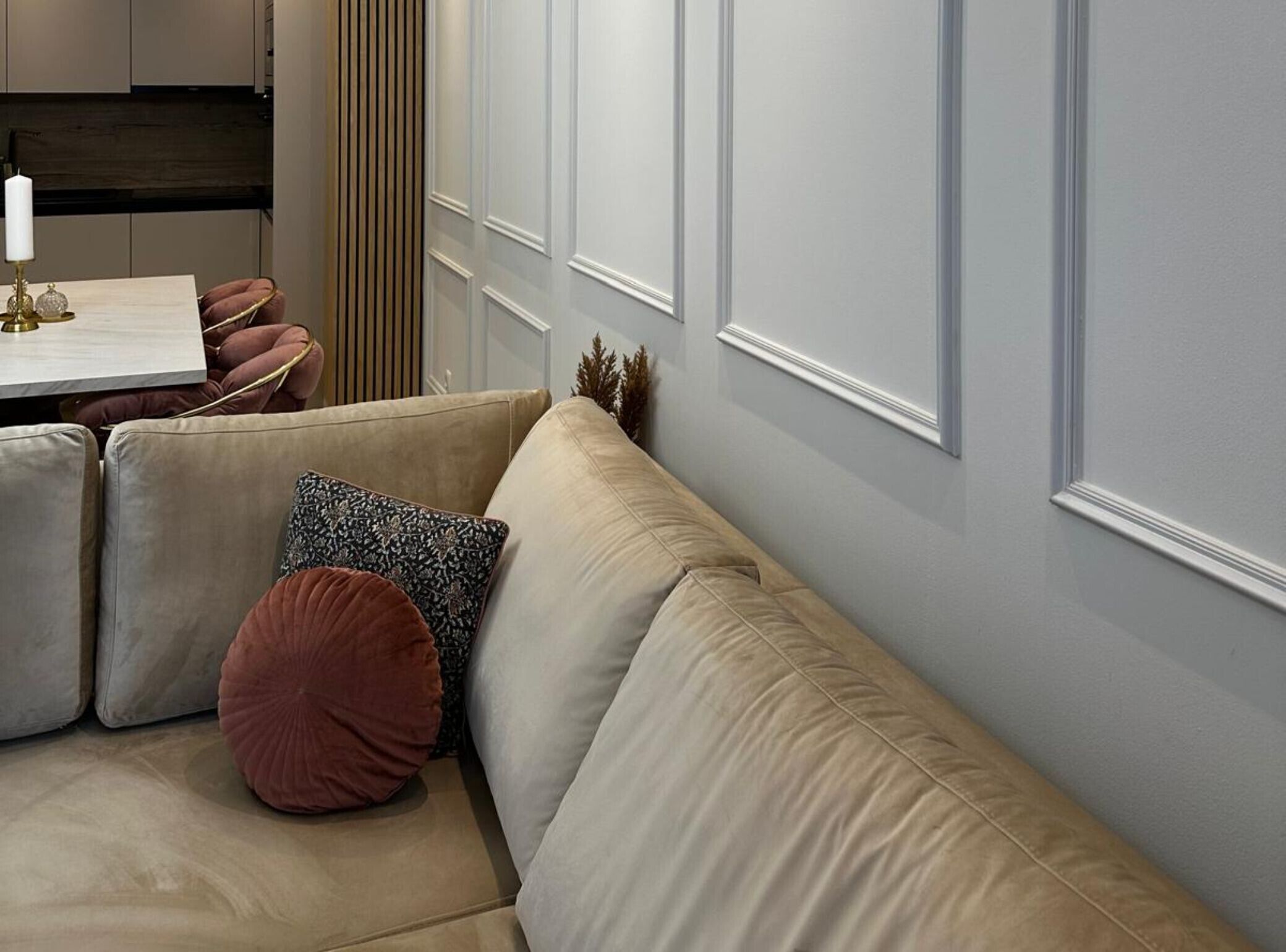 Un soggiorno moderno con un divano angolare beige, un tavolino con una candela e una pianta decorativa.
