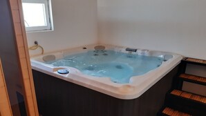 Ett bubbelbad i ett rum med trägolv och ett fönster.