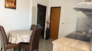 A compact kitchen with a dining table and chairs, a small sink, and a cabinet. - One Bedroom Apartment with Balcony (3) (Biograd na Moru)