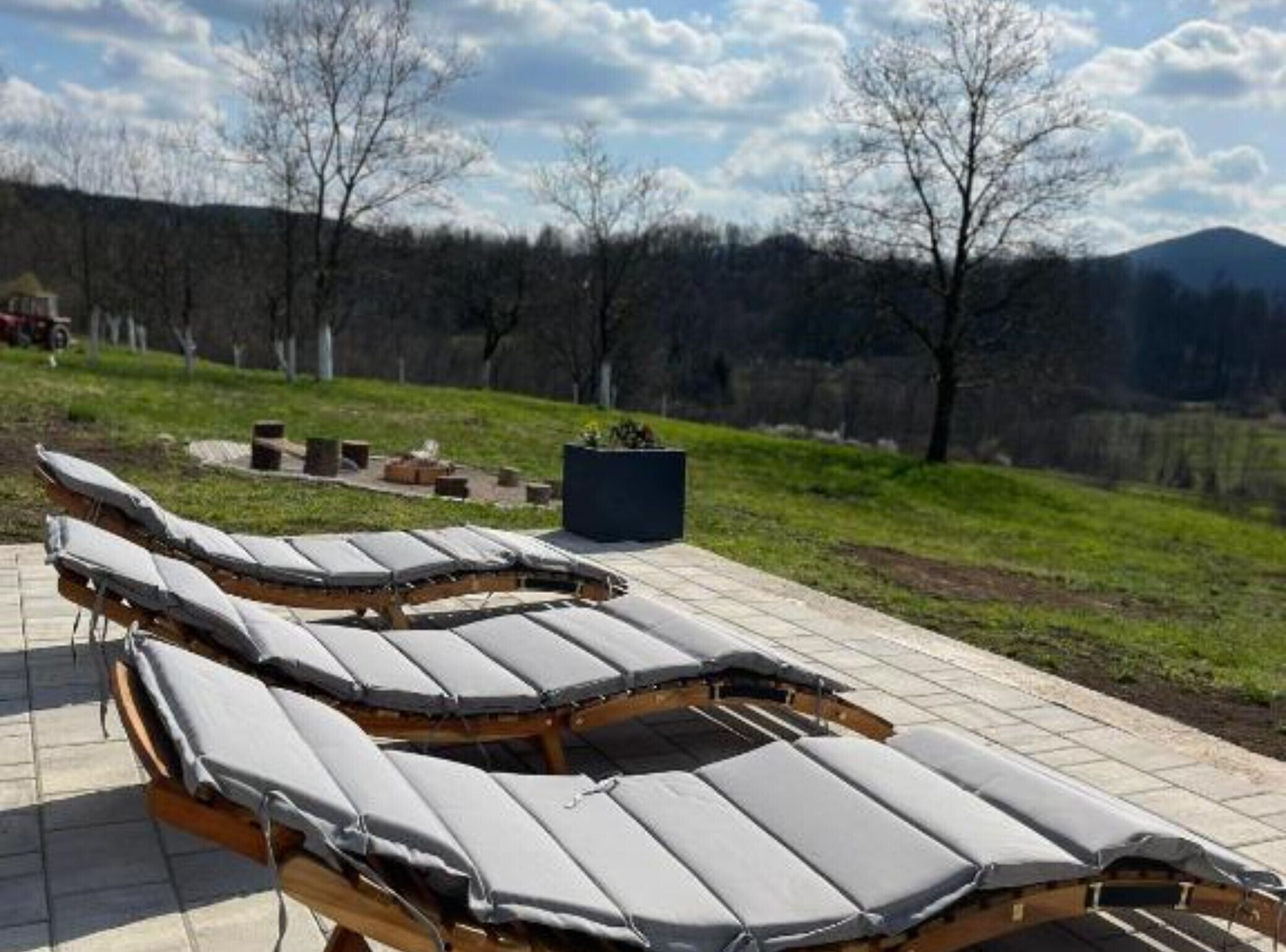 Outdoor sun loungers with a view of a forest and mountains.