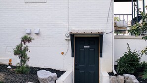 A white brick house with a black front door, a small window, and a covered porch area. - The Mane & Co - No. 4 (Chambersburg)