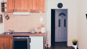 A kitchen with wooden cabinets, a sink, a stove, and a clock on the wall. - Hvar spa & apartments-1 Bedroom-Terrace/Sea View 3 (Vrboska)