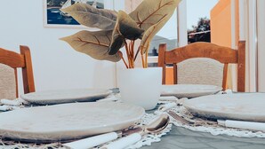 A dining table with a white vase containing a plant, surrounded by wooden chairs. - Hvar spa & apartments-1 Bedroom-Terrace/Sea View 3 (Vrboska)