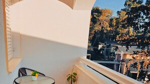 A balcony with a round table and two chairs, a potted plant, and a view of trees and buildings. - Hvar spa & apartment-2 Bedroom-Terrace/Sea View 4 (Vrboska)