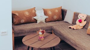 Ein gemütliches Wohnzimmer mit einer braunen Couch, einem runden Holztisch und einem Teddybär.